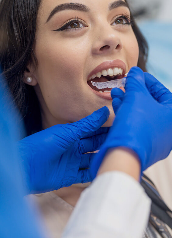 Dentist in blue gloves examining patient's teeth during dental checkup appointment.