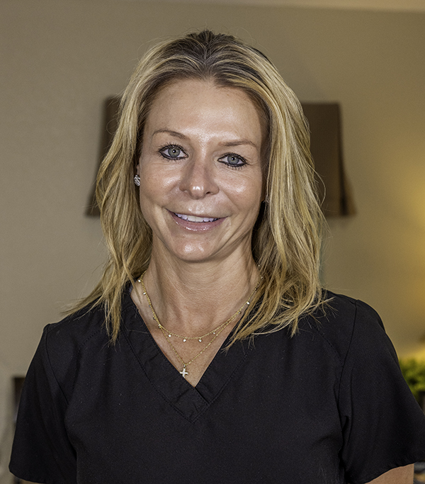 Professional woman smiling at camera in dental office wearing black v-neck top