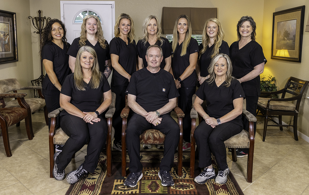 Cornerstone Dentistry team of women in black shirts posing together in office setting.
