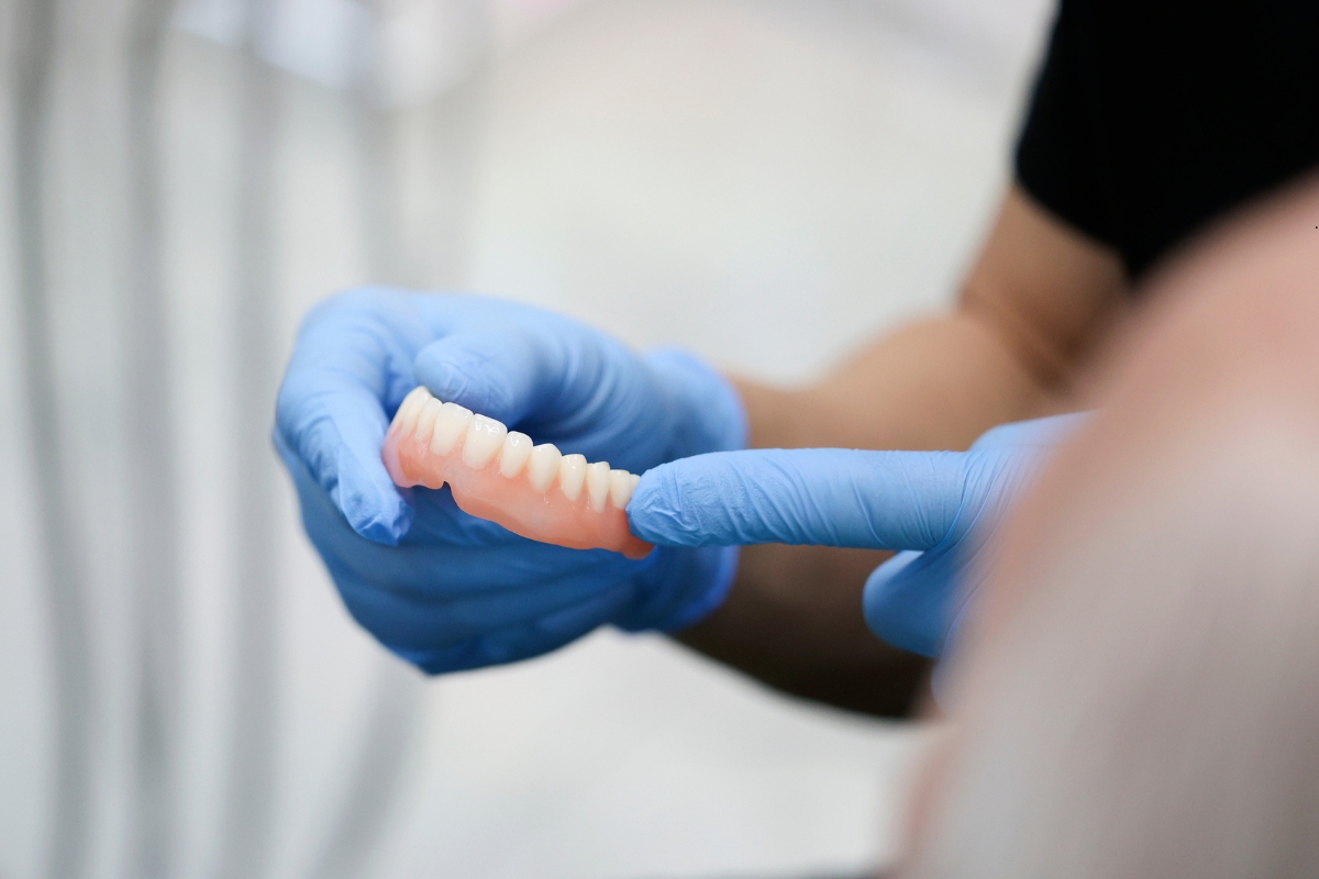 A Van dentist holding a denture