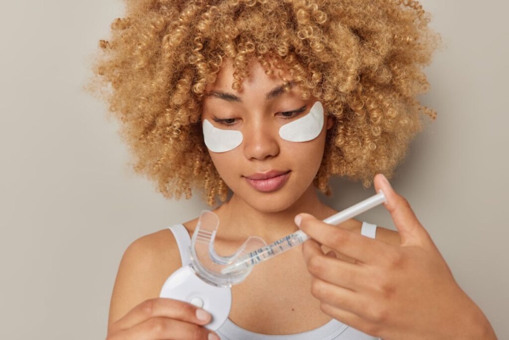 Woman using a store-bought teeth whitening kit at home